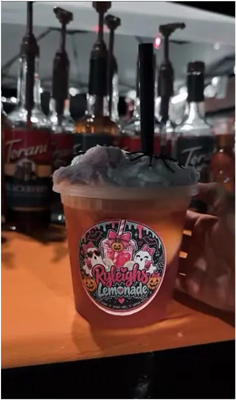 A Hocus Pocus lemonade topped with cotton candy and spiders, wearing the Ryleigh’s Lemonade Halloween sticker